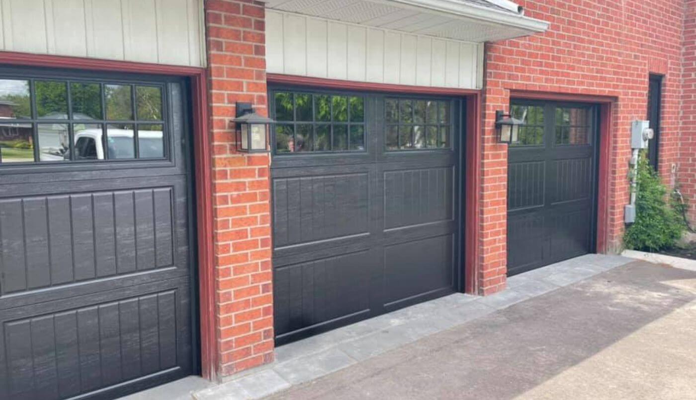 Three black garage doors on a building with red bricks, creating a bold and modern aesthetic for the property.