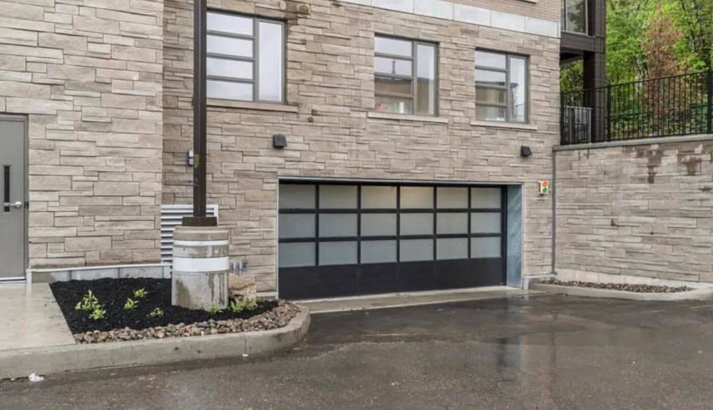 A Black California garage door on a stoned house.
