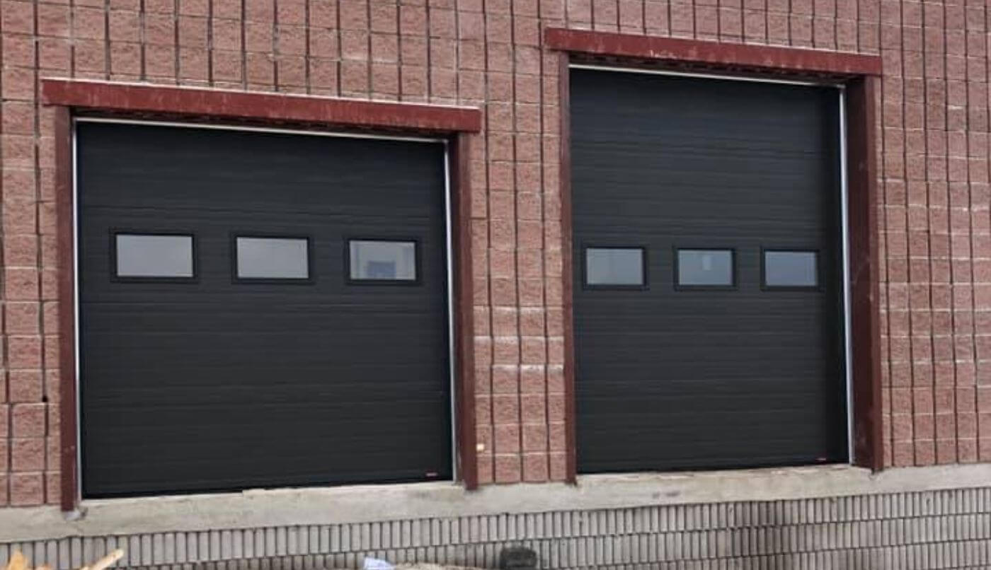 Two black commercial garage doors on a brick facade, illustrating an industrial style and robust architecture.