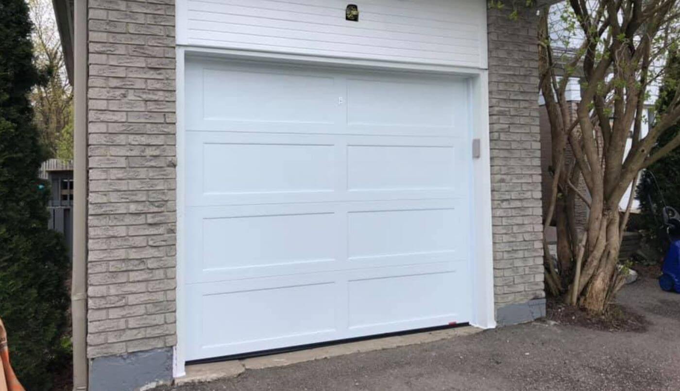 A white garage door stands prominently, showcasing its clean and simple design against a neutral backdrop.