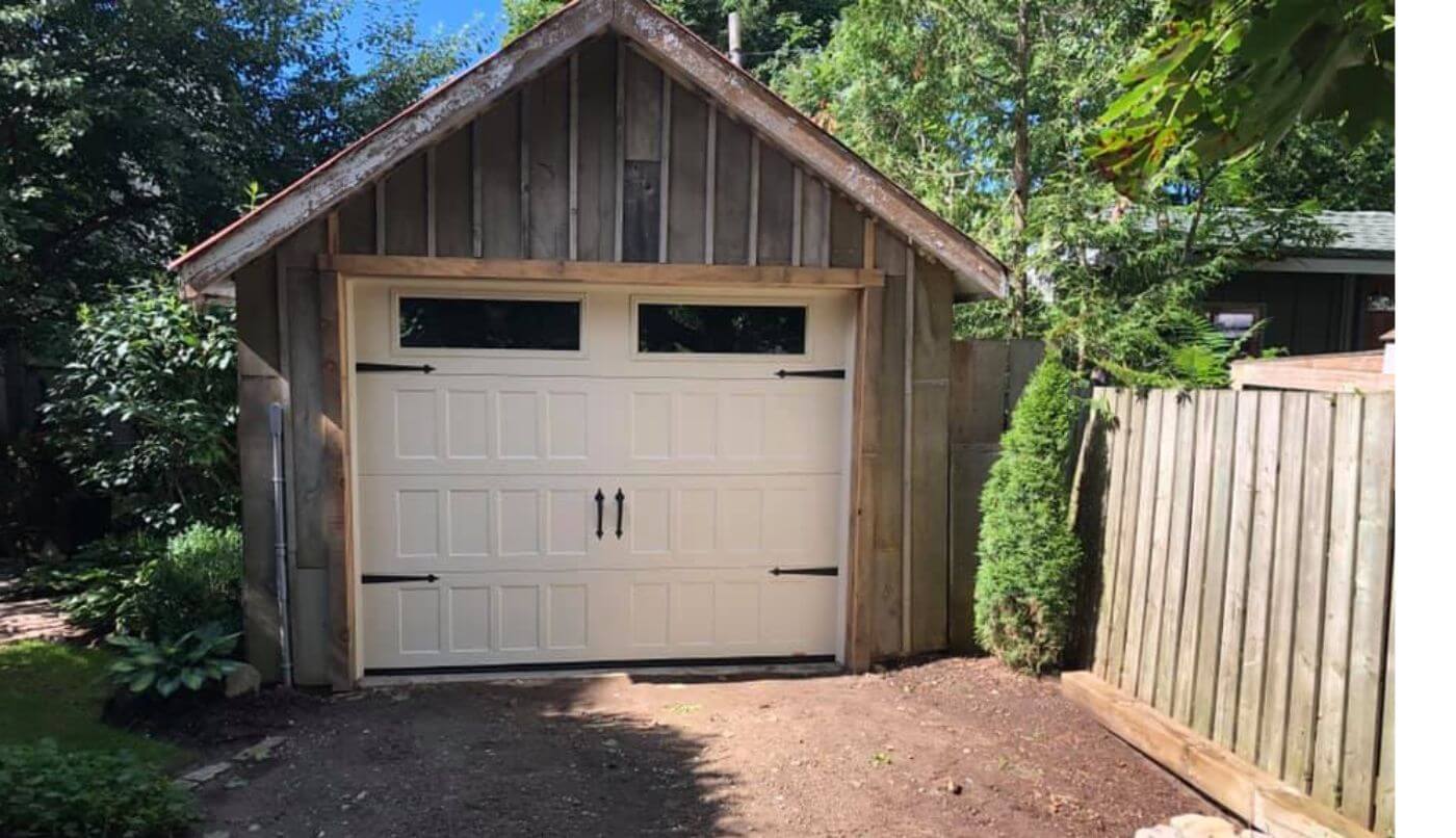 A garage door adjacent to a wooden fence, creating a rustic and cohesive outdoor aesthetic.