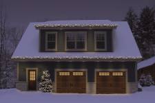 A garage by night, with 2 single garage doors. Their design is North Hatley LP, Their color is  Moka Brown, and they have 8 lite Orion windows